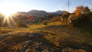 A rural landscape with a church, a cross, and mountains in the background. - Paderlafoderhof Apartment 1, Zentrale Lage mit Garage (Lajen)