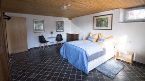 A bedroom with a bed, a desk, a chair, and artwork on the walls.