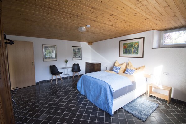A bedroom with a bed, a desk, a chair, and artwork on the walls.