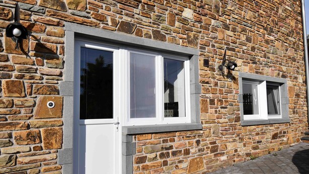 A stone building with two white-framed windows and a small door.
