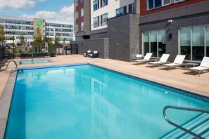 A swimming pool with lounge chairs and a building in the background. - Hyatt Place Boise/Meridian (Meridian)