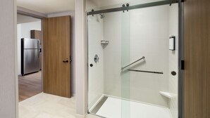A modern bathroom with a glass-enclosed shower, a wooden door, and a stainless steel refrigerator in the adjacent room. - Hyatt Place Boise/Meridian (Meridian)