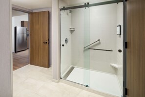 A modern bathroom with a glass-enclosed shower, a wooden door, and a stainless steel refrigerator in the adjacent room. - Hyatt Place Boise/Meridian (Meridian)