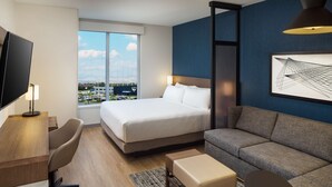 A hotel room with a bed, a sofa, a desk, and a TV. - Hyatt Place Boise/Meridian (Meridian)