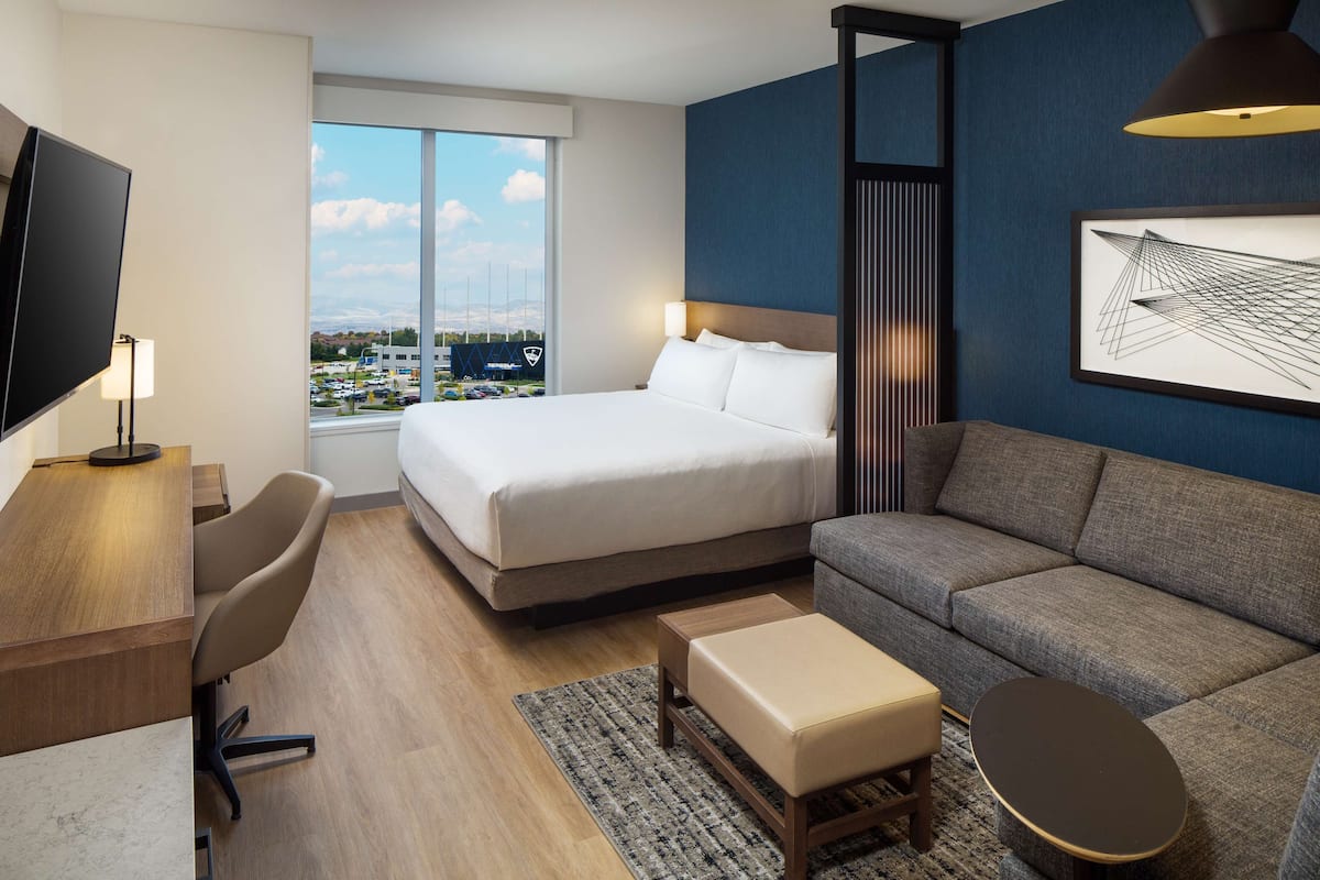 A hotel room with a bed, a sofa, a desk, and a TV.