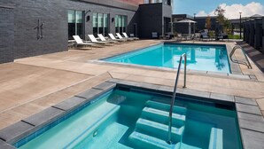 A swimming pool with steps and lounge chairs, surrounded by a patio area with a modern building in the background. - Hyatt Place Boise/Meridian (Meridian)