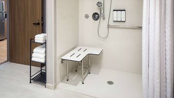 A modern bathroom with a shower, a towel rack, and a shelf with toiletries.