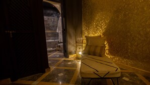 A room with a checkered floor, a bed with a headboard, a nightstand, and a wall-mounted light fixture. - Riad SofYan (Marrakech)