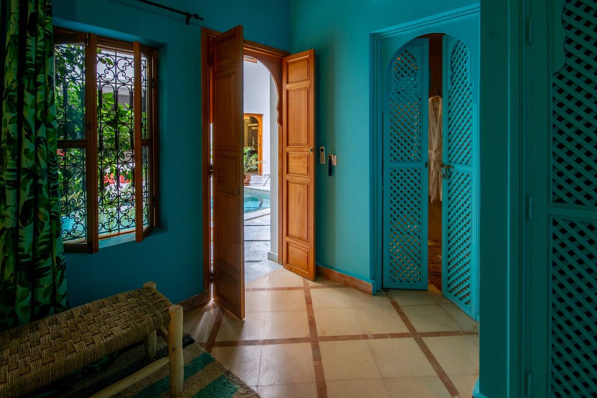 A hallway with a bench, a wooden door, and a view of an outdoor area.
