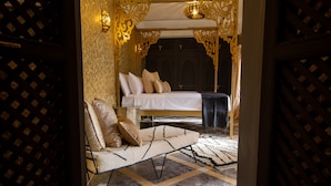 A luxurious bedroom with a large bed, a sofa, and a patterned floor. - Riad SofYan (Marrakech)