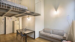 A compact room with a bunk bed, a kitchenette, a dining area, and a sofa. - Modern Loft in Porta Venezia (Milan)