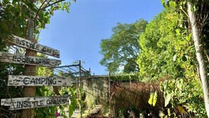 A rustic wooden signpost with directions to various amenities including a cafe, food and drink, camping, and a garden. - Instyle place (Chiang Rai)