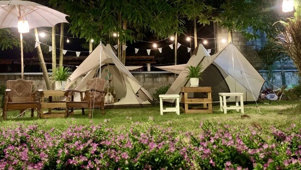 A campsite with tents, a table, chairs, and string lights. - Instyle place (Chiang Rai)