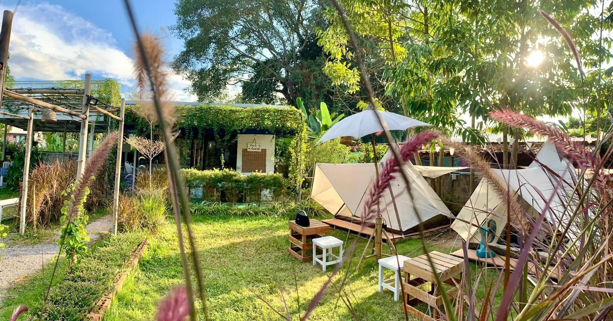 A campsite with tents, a wooden table, and a covered seating area.