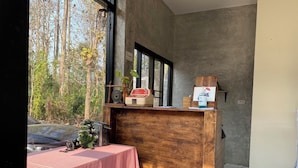 A room with a wooden desk, a checkered table, and a view of trees outside. - Instyle place (Chiang Rai)
