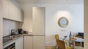 A modern kitchen with a built-in oven, a coffee maker, and a toaster. There is a dining area with a glass table and yellow chairs. - Milan Luxury Gem (Milan)