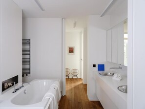 Een moderne badkamer met een ruime badkuip, een wit wastafel en een spiegel.