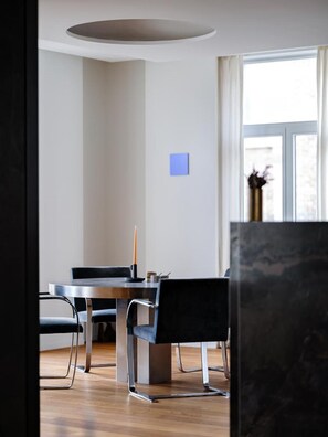Een moderne eethoek met een ronde tafel, zwarte stoelen en een kaars.