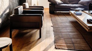 A modern living room with a dark wall, a sofa, a coffee table, and a rug. - Magnificent High-end 2-bedroom Apartment in Gent (Ghent)