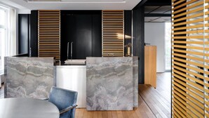 A modern kitchen with a central island, black cabinets, and wooden slatted blinds. - Magnificent High-end 2-bedroom Apartment in Gent (Ghent)