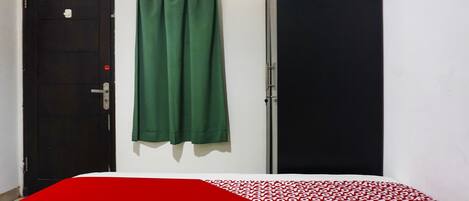 A room with a bed, a black door, and a green curtain.