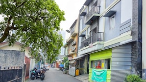 A narrow street lined with multi-story buildings, some with balconies and satellite dishes.