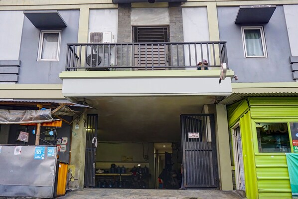 Een gebouw met een balkon, een overdekte ingang en een groene gevel.