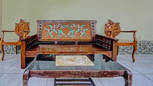 A wooden sofa with intricate floral carvings, a glass coffee table, and matching wooden armchairs. - OYO Life 91268 Homestay Bu Erma Syariah (Palembang)
