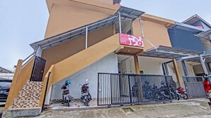 A modern building with a unique angular design, a gated entrance, and a staircase leading to the entrance. - OYO Life 91268 Homestay Bu Erma Syariah (Palembang)