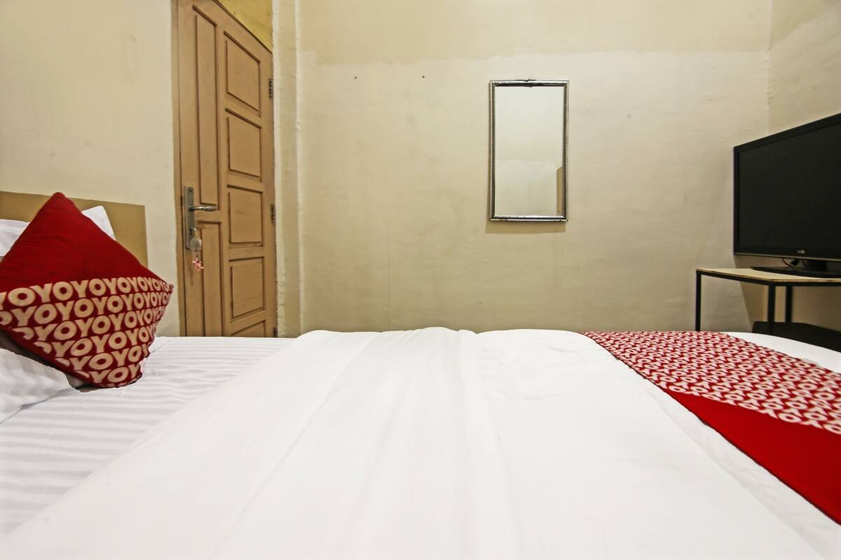 Ein Hotelzimmer mit Bett, Fernseher, Spiegel und Tür.