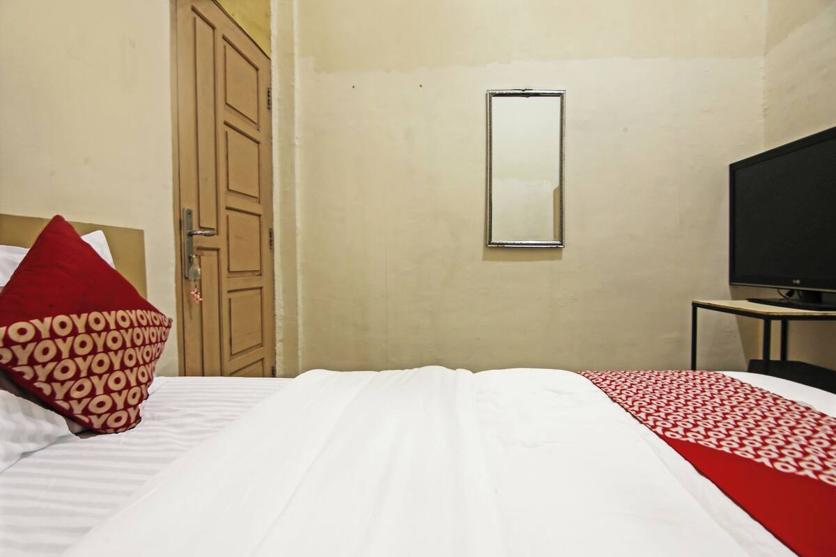Ein Hotelzimmer mit Bett, Fernseher, Spiegel und Tür.