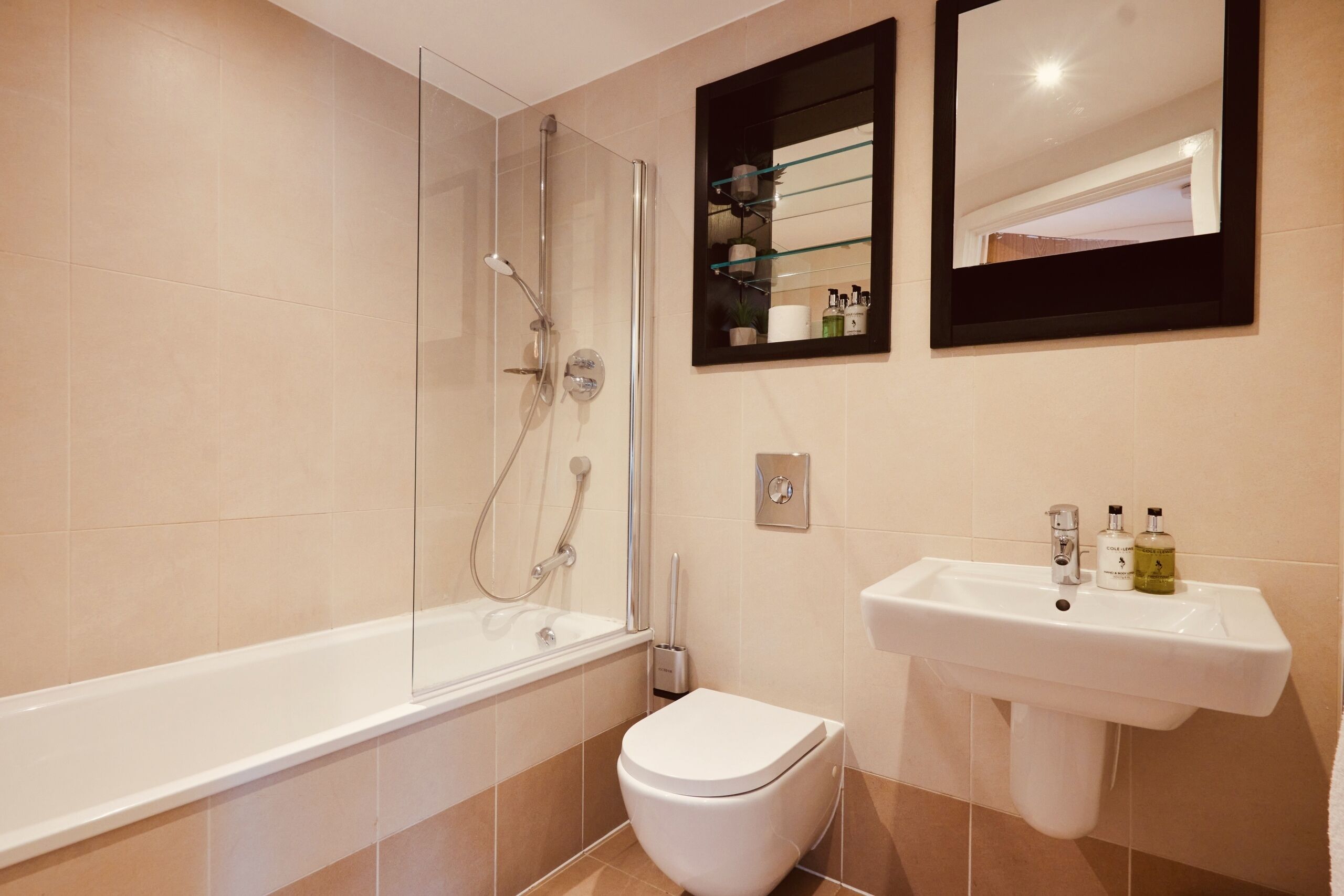 A modern bathroom with a glass-enclosed shower, a white toilet, and a sink with toiletries.