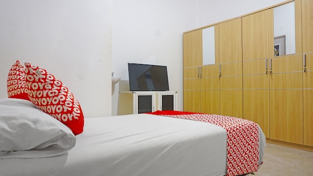 A bedroom with a bed, a TV, a wardrobe, and a sink.