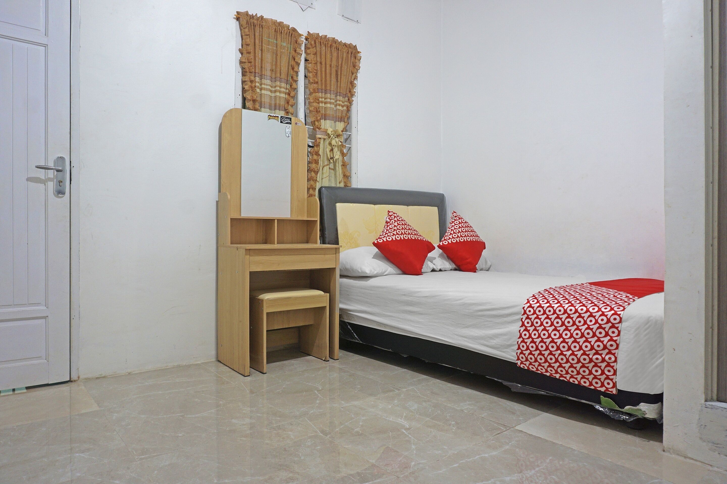Ein Schlafzimmer mit einem Bett, einem Holztisch, einem Stuhl, einem Spiegel und einem Kleiderschrank.
