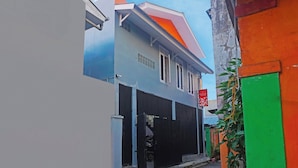 A narrow street with a building featuring a black gate and a red sign.