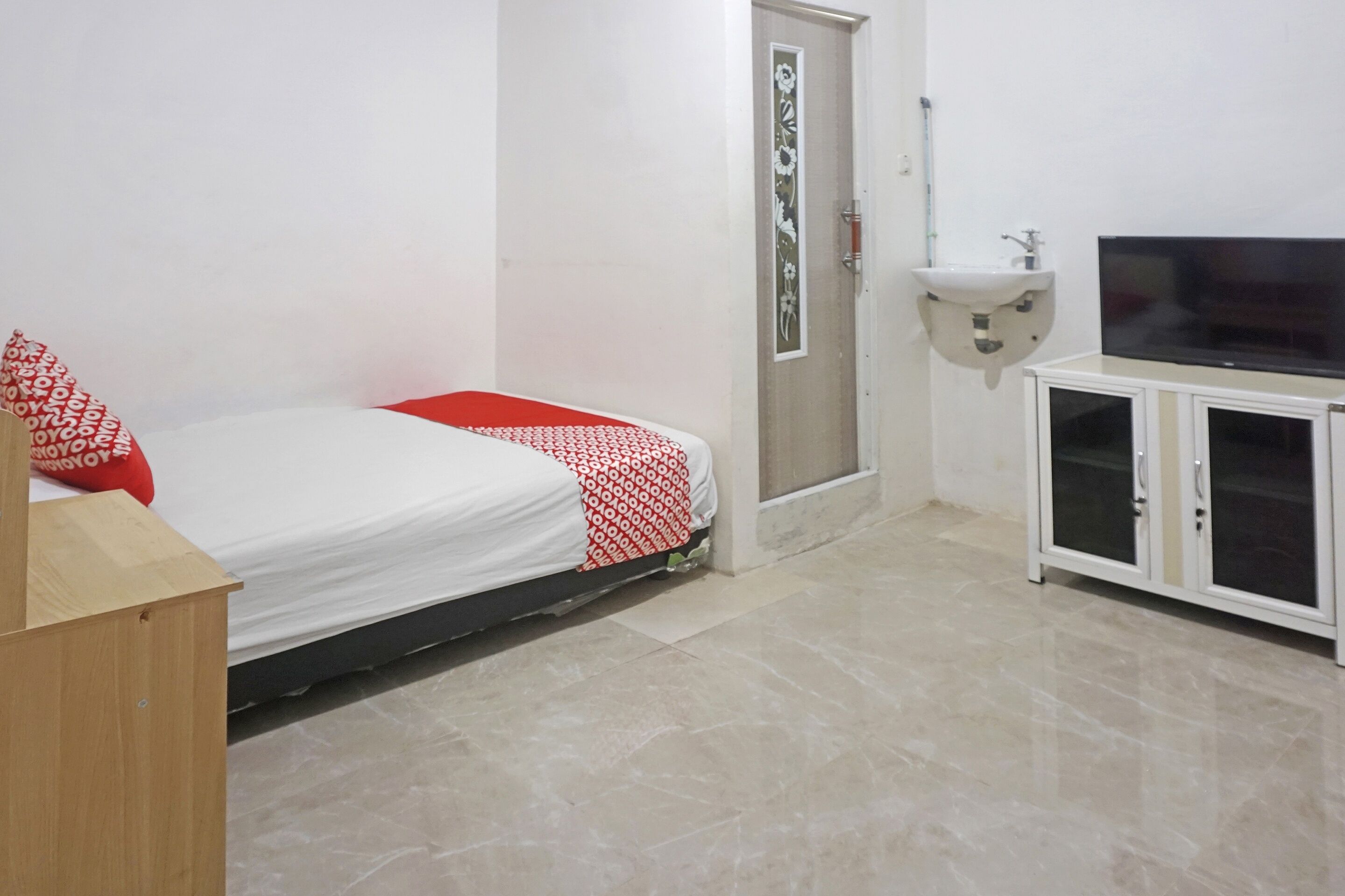 A room with a bed, a TV, a cabinet, and a door.