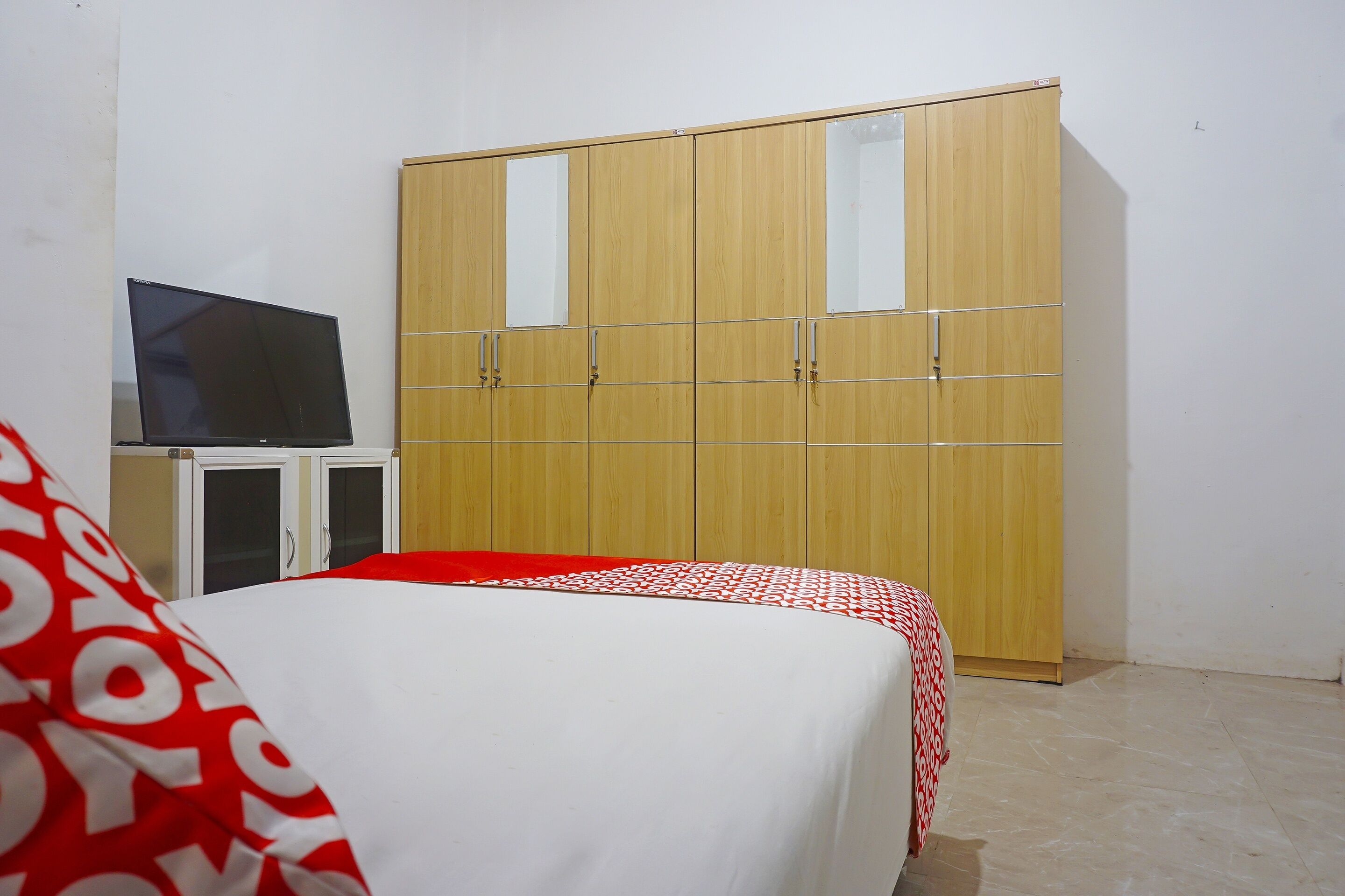 Une chambre à coucher avec un lit, une armoire et un téléviseur posé sur un meuble.