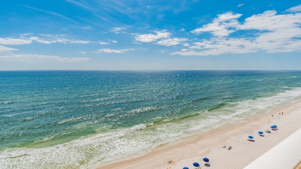 Ein Strand mit blauem Himmel, Wellen und Menschen.