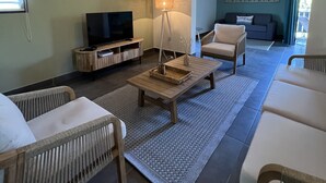 Een woonkamer met een televisie, een salontafel en twee banken.