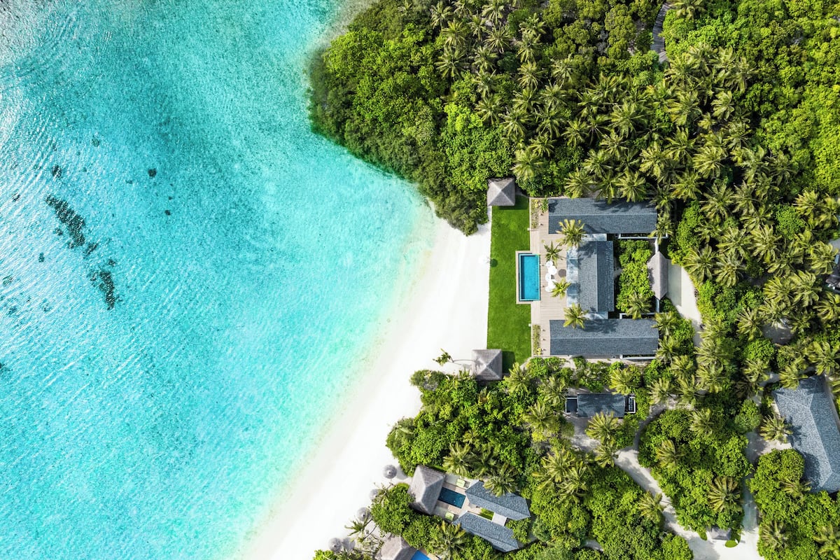 Eine Luftaufnahme eines tropischen Resorts mit Pool, mehreren Villen und üppiger Vegetation.