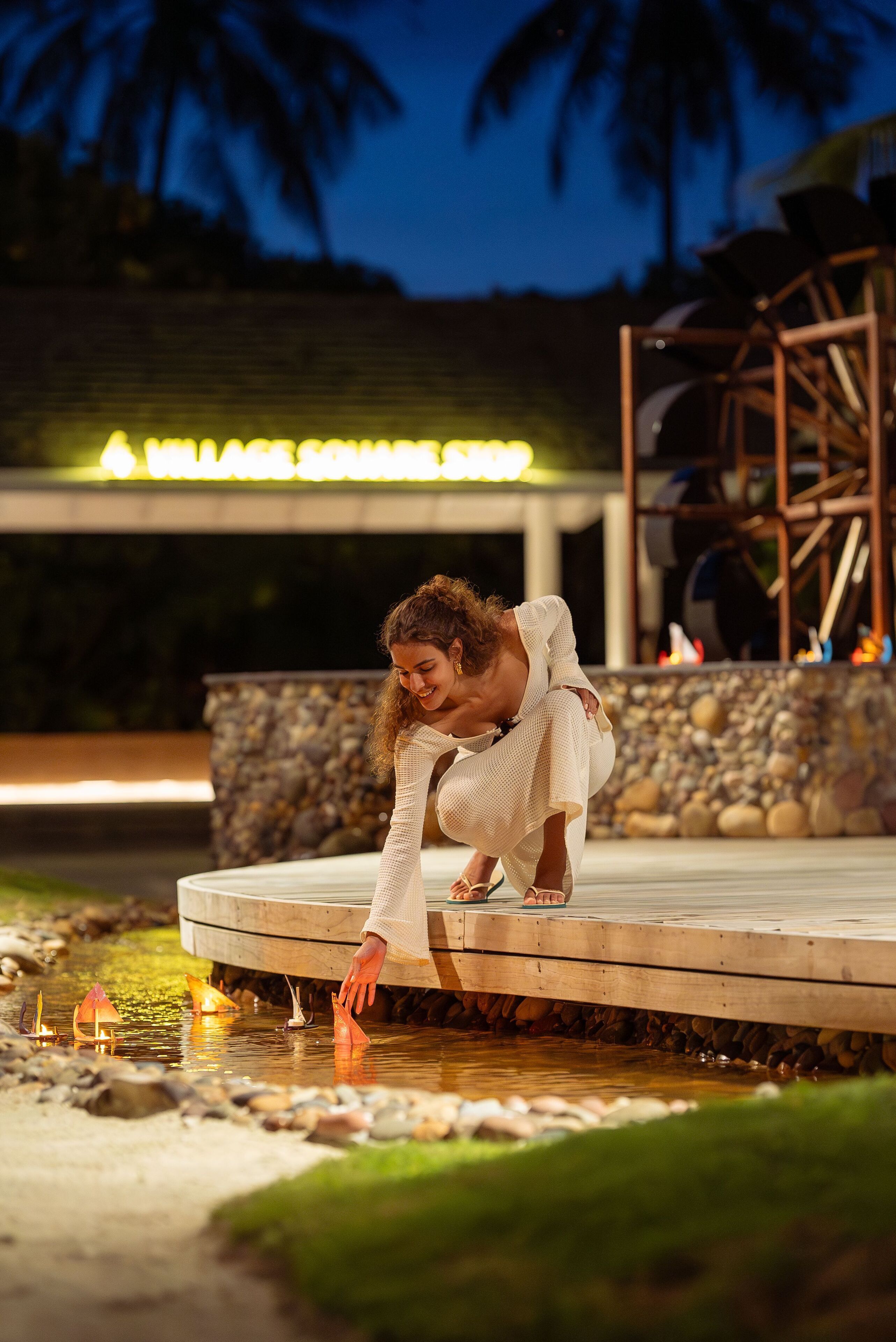 A person on a wooden deck by a body of water at night.