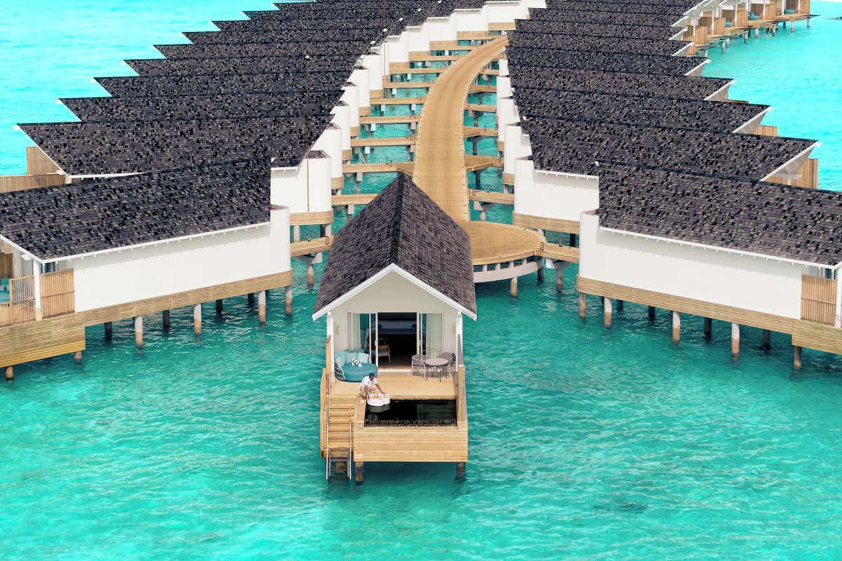 Eine Reihe von überwasserbungalows mit Holzterrassen und Infinity-Pools, verbunden durch Wege.