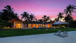 Un resort moderno con piscina, mobiliario exterior y palmeras.