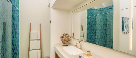 A modern bathroom with a large mirror, white sink, and a towel rack.