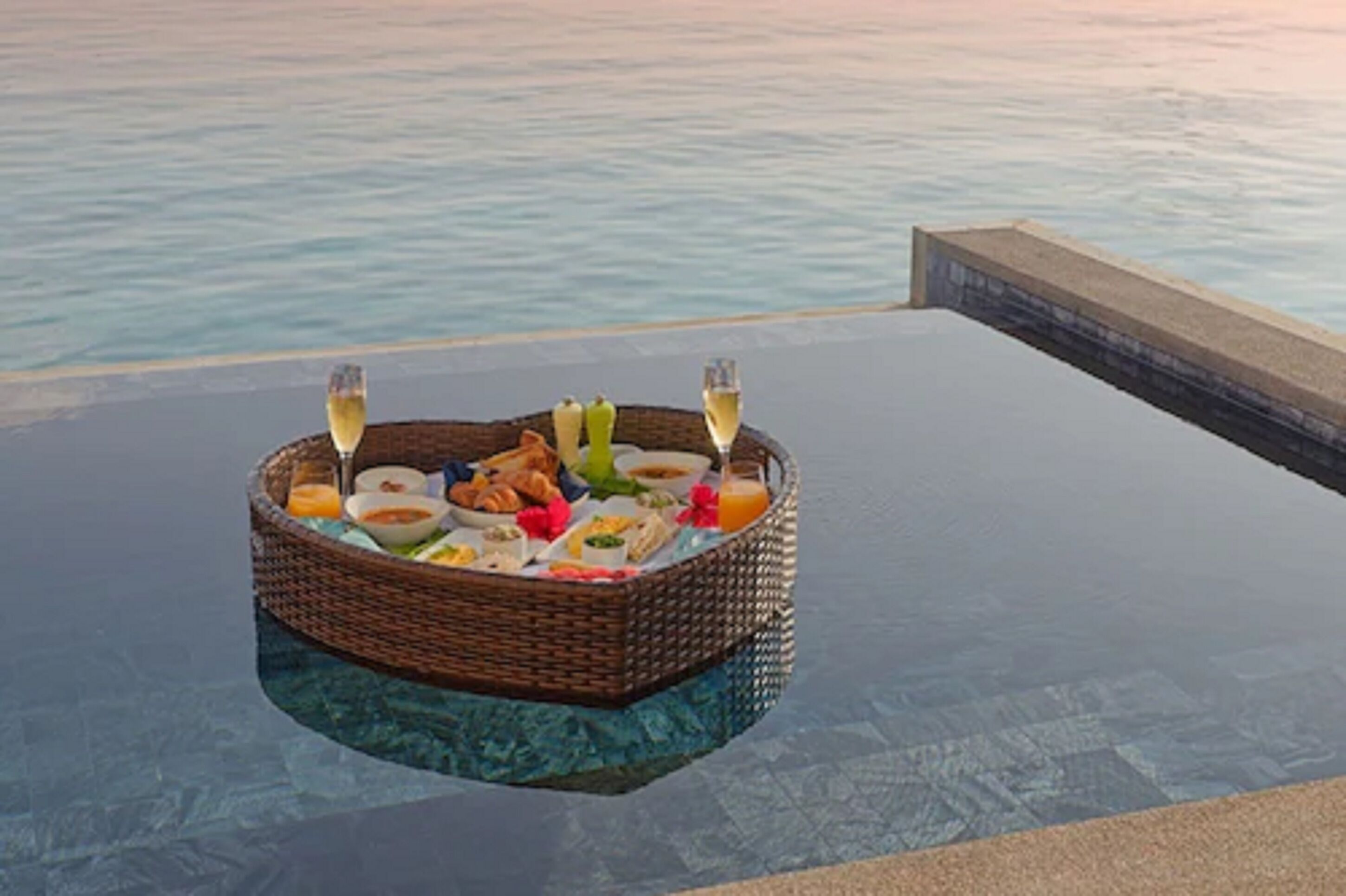 A floating dining table with a wicker basket containing food and drinks, overlooking a body of water.
