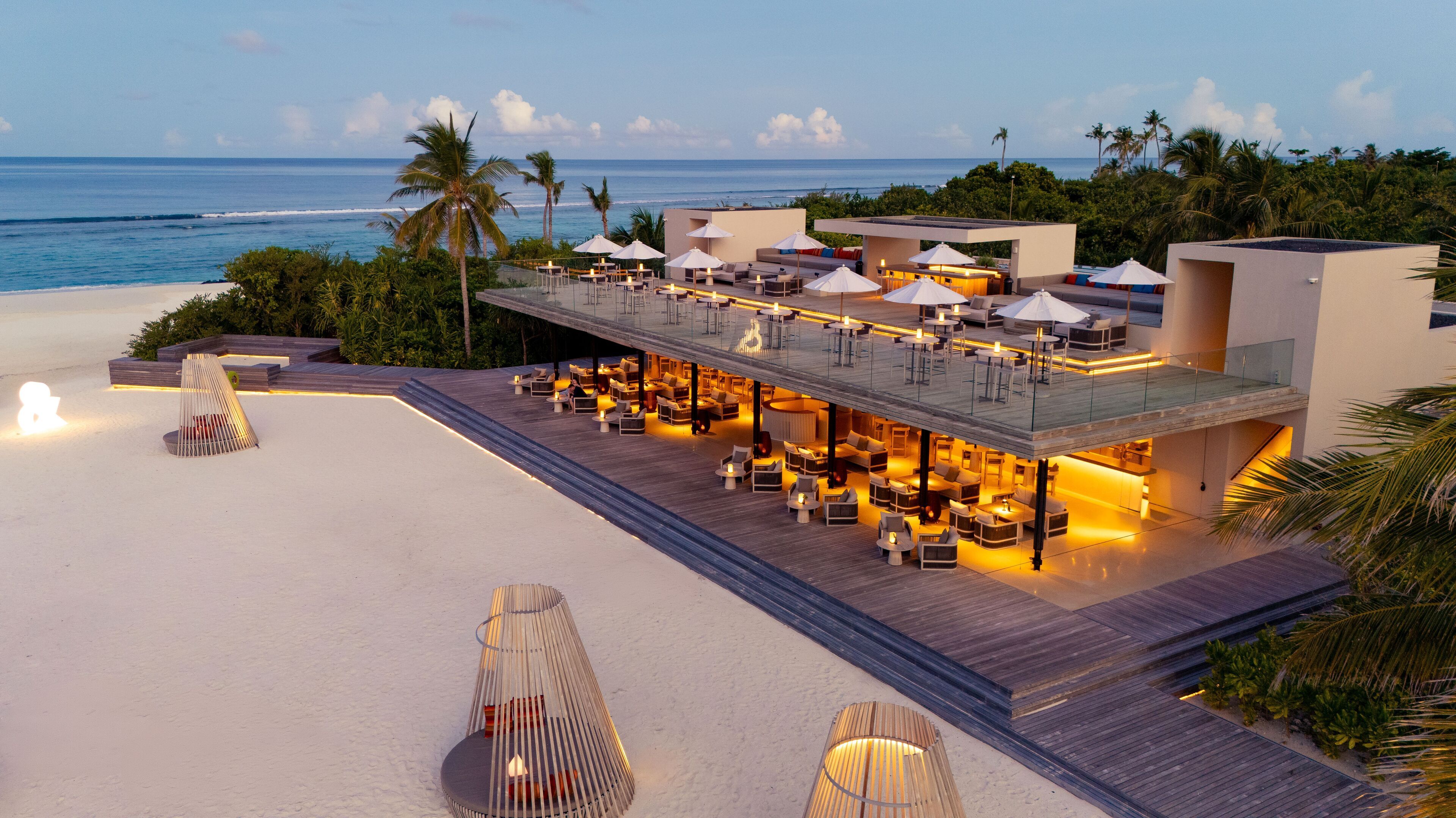 Un resort frente a la playa con zonas de estar al aire libre, piscina y vista al océano.