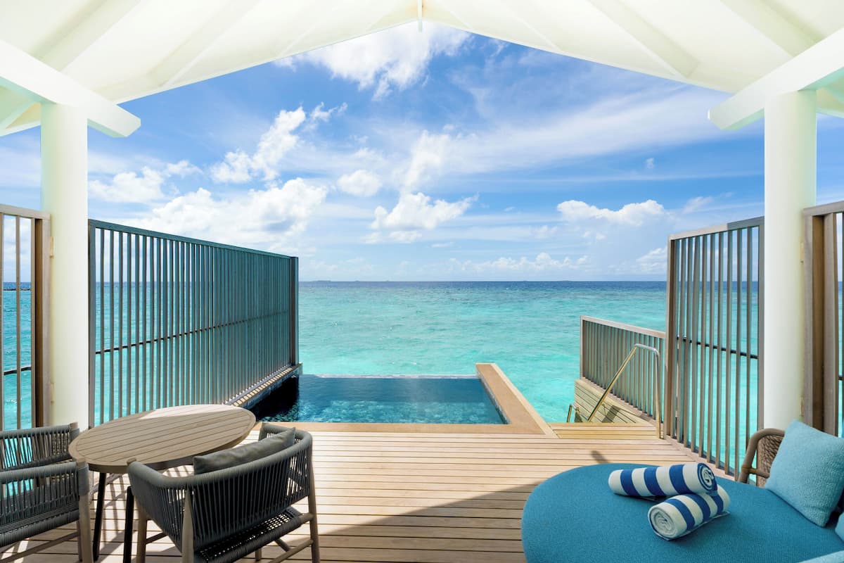 Eine Holzterrasse mit Pool, Liegestühlen und Meerblick.