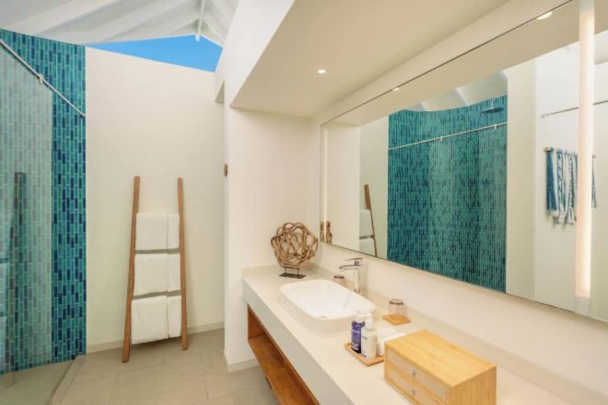 Un baño moderno con tragaluz, un espejo grande y un lavamanos blanco.