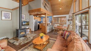 A spacious living area with a fireplace, leather sofa, and a dining table with chairs. - Jack's Cabin 2 Bedroom Home by NW Comfy Cabins (Leavenworth)