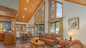 A spacious living room with a high ceiling, large windows, a dining area, and a kitchen. - Jack's Cabin 2 Bedroom Home by NW Comfy Cabins (Leavenworth)